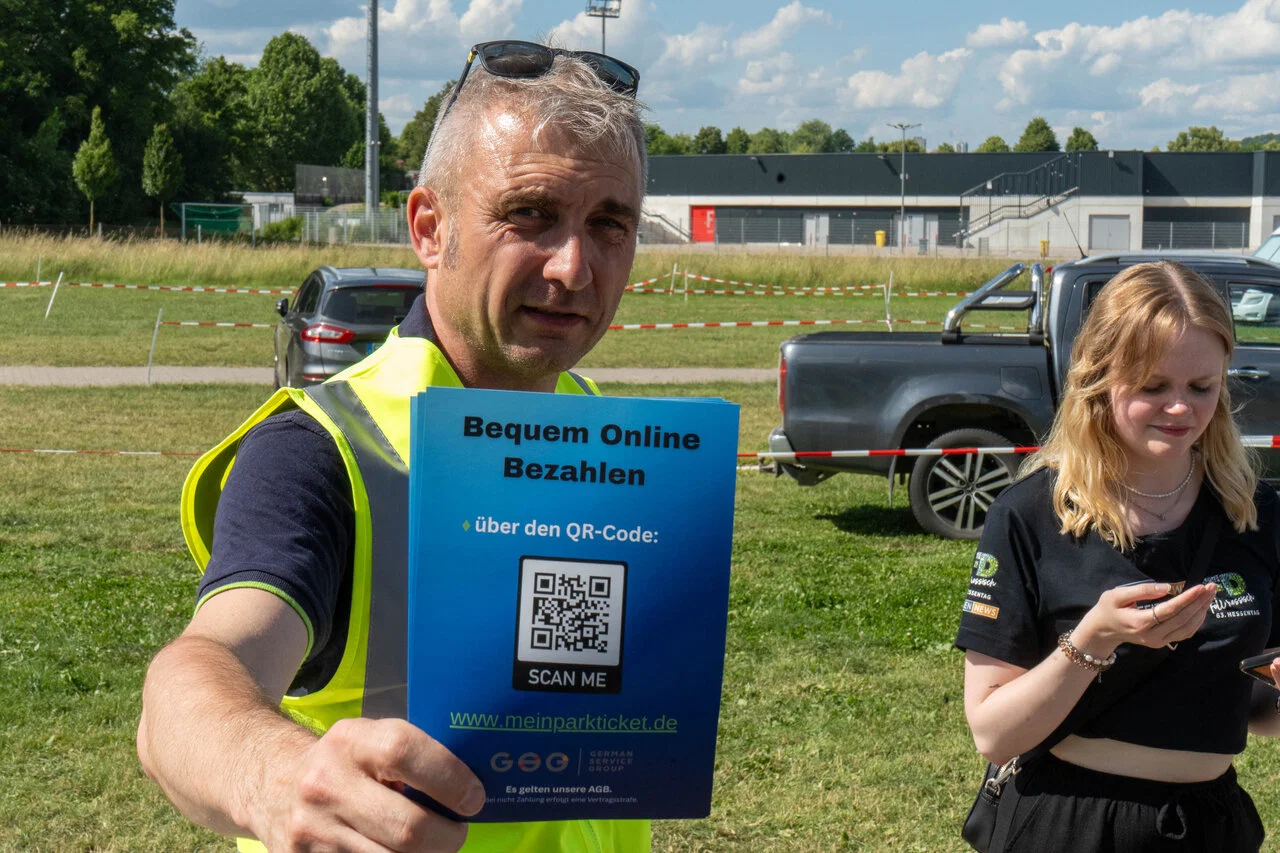 Mitarbeiter beim Hessentag 2026 in Fulda mit QR-Code-Schild für die digitale Bezahlung über meinparkticket.de