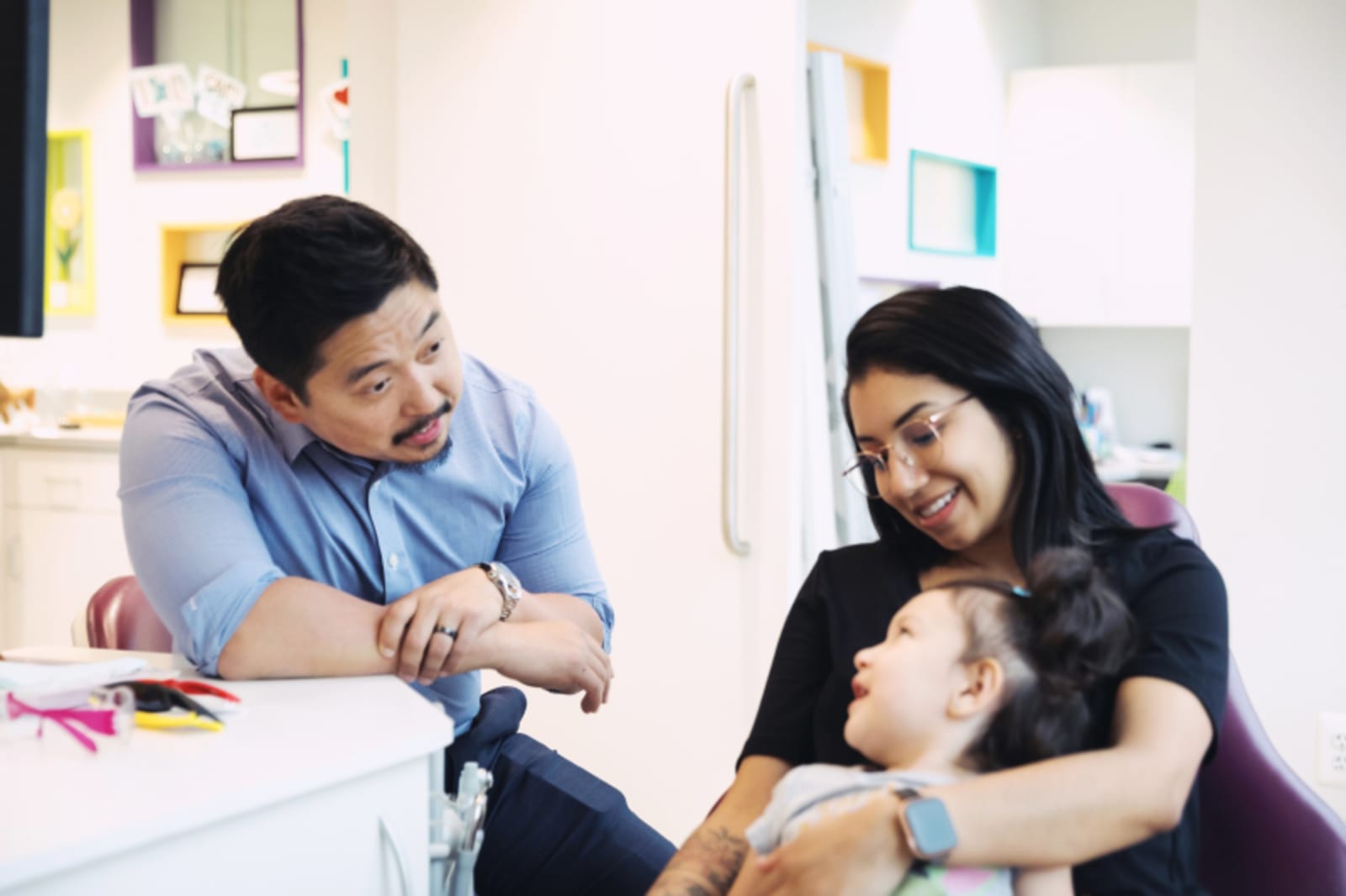 Child's first Invisalign appointment showing clear aligner trays and orthodontist consultation with parent present
