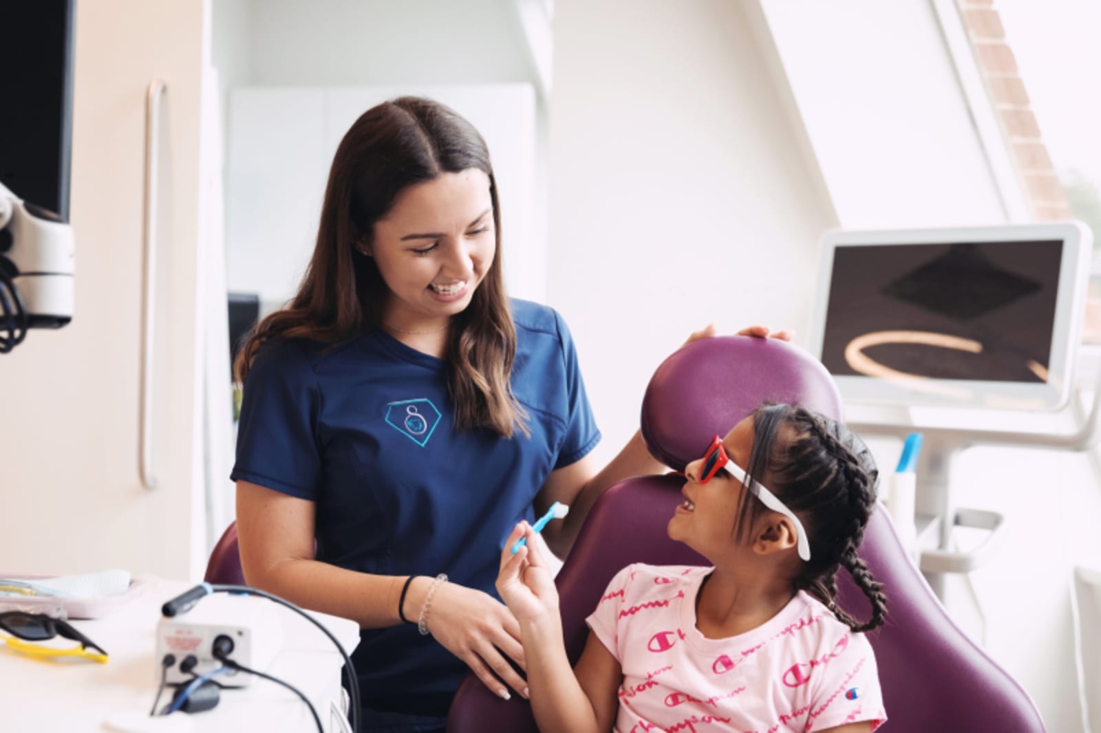 Female dental professional examining a young child patient in dental chair