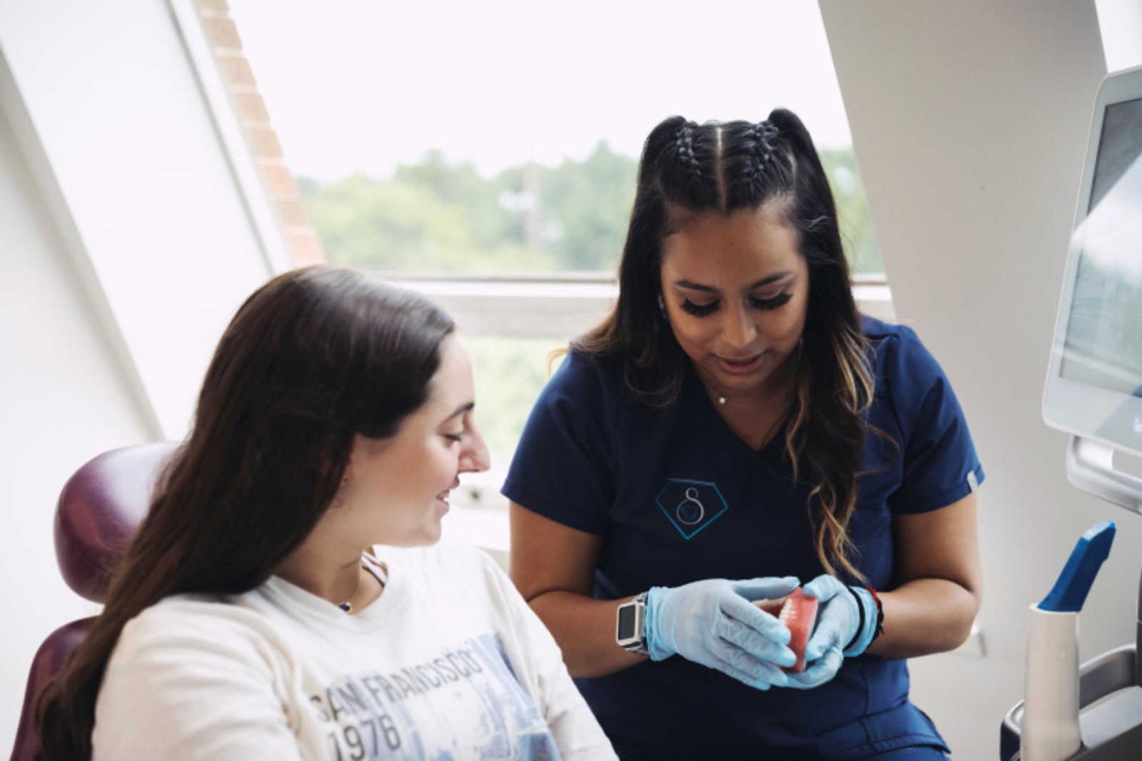 Pediatric dentist showing teen patient clear aligner treatment option during office consultation.