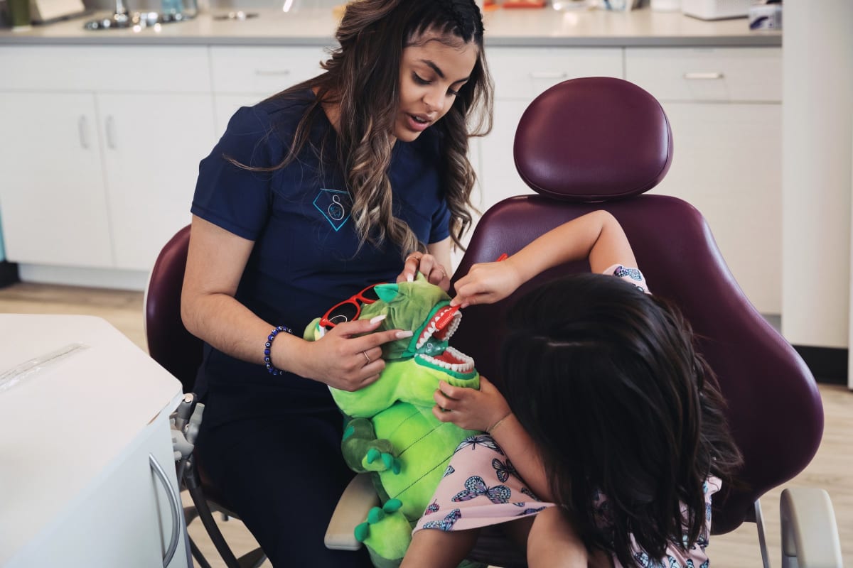 Pediatric dentist examining a young child in the dental chair during treatment