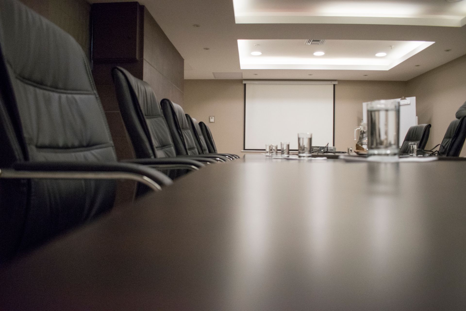 Black leather chairs lined up along a long, empty conference table