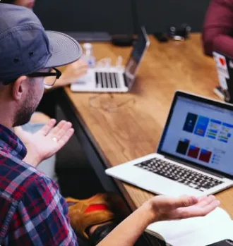 Man wearing hat looking at a Laptop