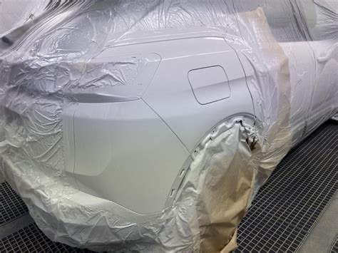 Véhicule masqué en cabine de peinture, élément en apprêt avant mise en teinte : des heures de préparation qui disparaîtront sous la peinture finale