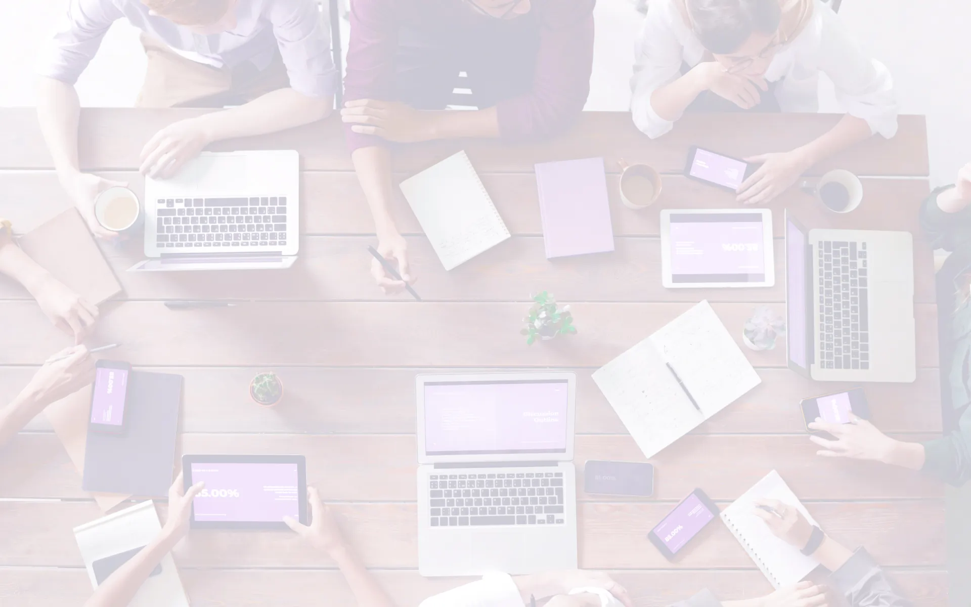 Mesa de reunião com computadores, papéis e canetas.