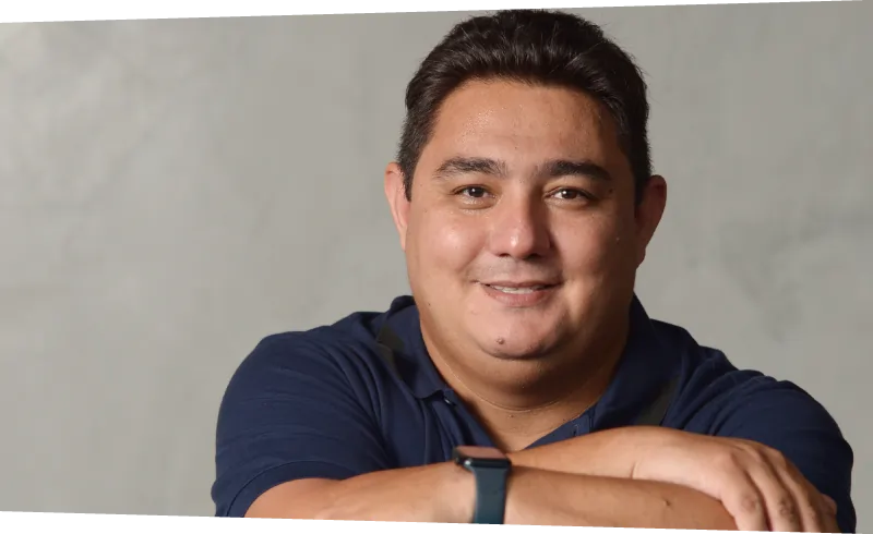 Foto de Danilo Yoneshige, CEO da Layers Education. Homem pardo, cabelos e olhos castanhos, de camisa polo azul marino.