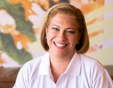 Foto da Dra. Lara Crivelaro, Diretora Acadêmica do Instituto Educbank. Mulher branca, loira, de olhos verdes e camisa polo branca.