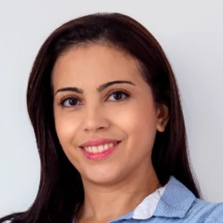 Aline Cruz. Mulher branca, de cabelos e olhos pretos, de camisa social azul e branca.