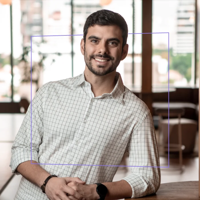 Caio Noronha. Homem branco de olhos, barba e cabelos castanhos com camisa social branca e cinza.