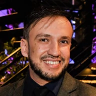 Rafael Matsudo, CEO do Colégio Le Petit Nicolá. Homem branco de cabelos e olhos castanhos, barba, veste terno cinza e camisa azul-marinho.