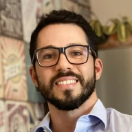Bernardo Rangel. Homem branco de olhos, barba e cabelos castanhos de óculos e com camisa social azul clara.