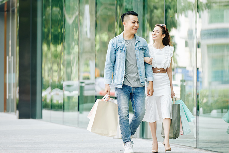 A young couple walks together down a street holding shopping bags