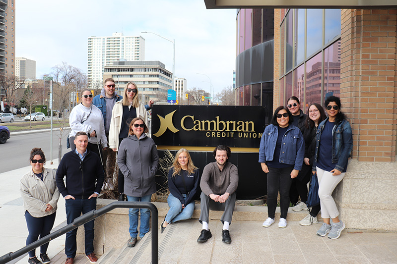 A group of people stand around a Cambrian Credit Union sign