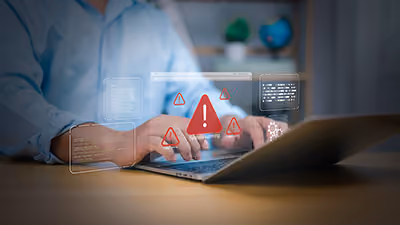 Person typing on laptop with digital warning icons and error messages hovering above the keyboard.