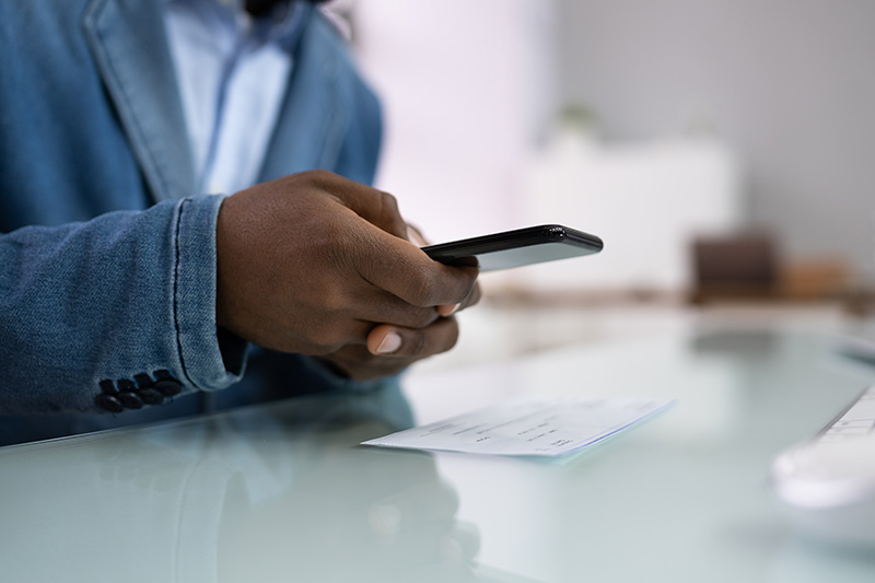 Some hands poised to take a picture of a cheque at a table