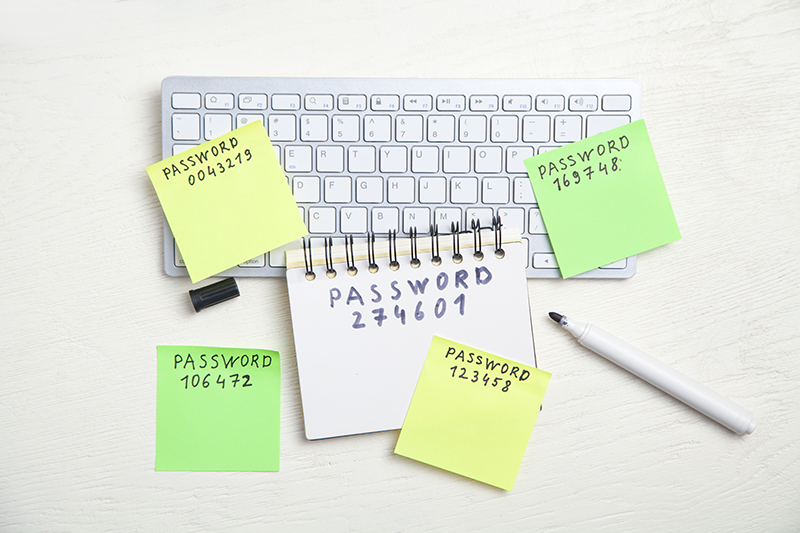 Various passwords written on sticky notes and a notebook on top of a keyboard