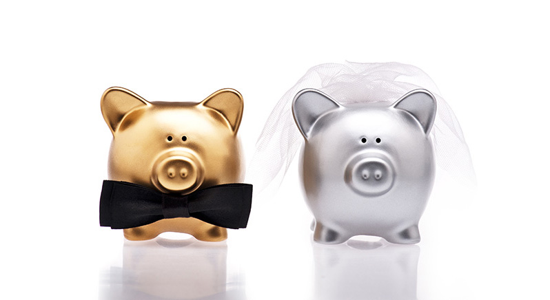 A gold piggy bank with a black bowtie and a silver piggy bank with a veil, side by side