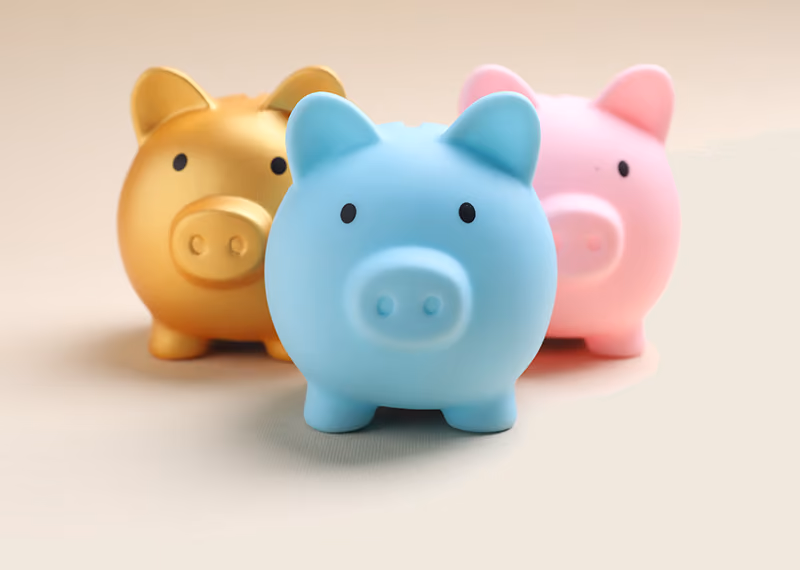 Three piggy banks: one gold, one blue, and one pink, the blue one in front