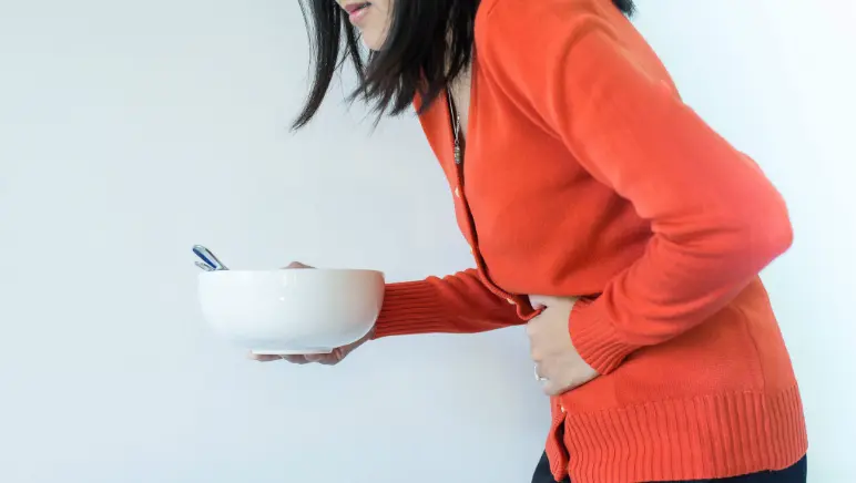 Woman holding chest with discomfort, symbolizing heartburn or hiatal hernia pain.
