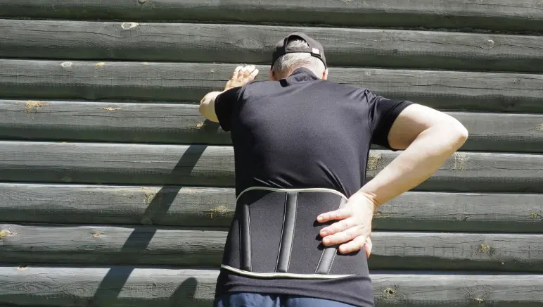 Person wearing a hernia support belt around abdomen for relief.