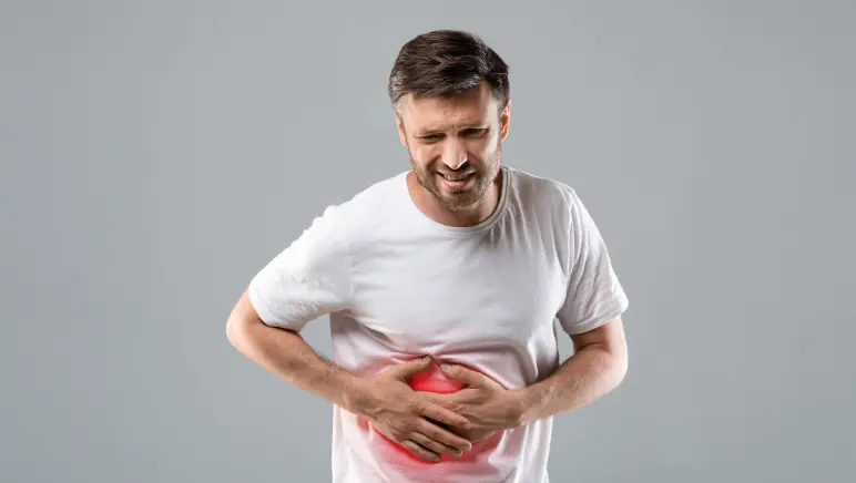 Patient holding abdomen in severe pain, likely due to a hernia.