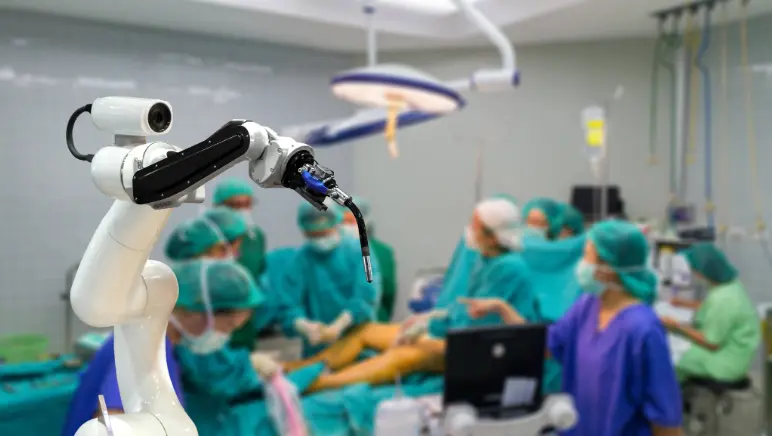 Surgeon at robotic surgery console guiding robotic arms during hernia repair.