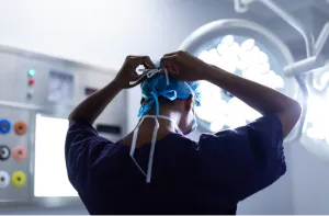 Hernia surgeon preparing for minimally invasive surgery under bright operating room lights.