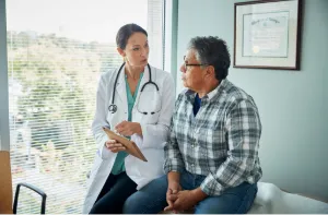 Female hernia specialist reviewing medical information with a male patient during an in-office consultation.