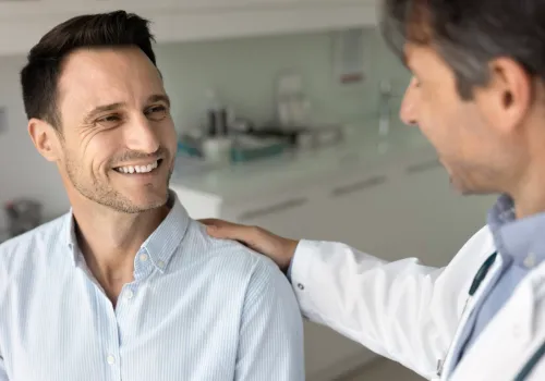 Doctor reassuring a smiling patient during a consultation after determining surgery is not required.