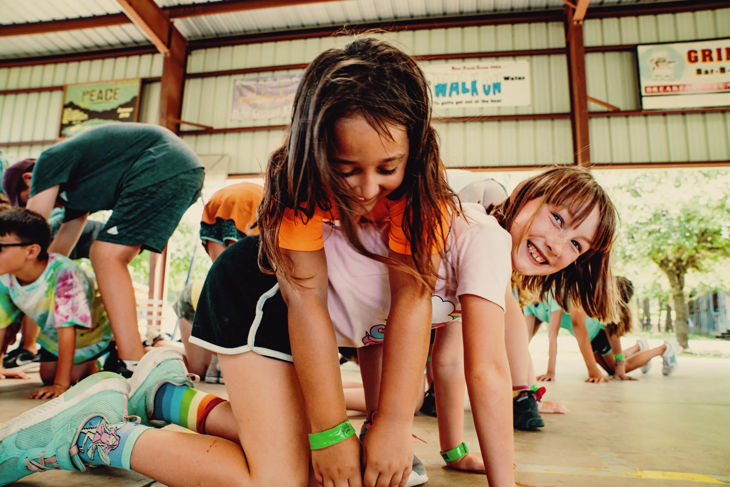 Smiling girl crawling during an outdoor camp game with other kids