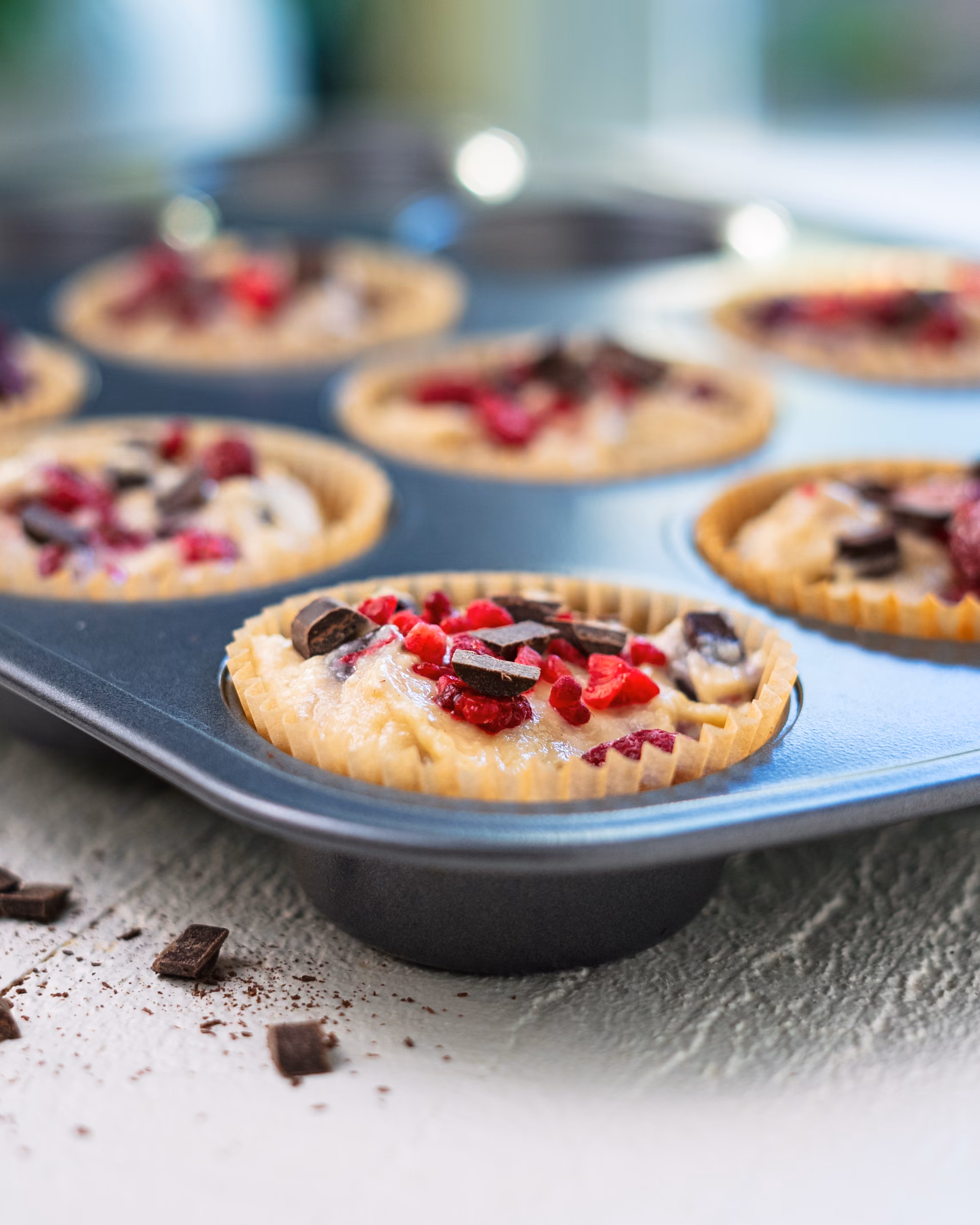 Vegan raspberry chocolate chip muffins in a muffin tin fresh from the oven