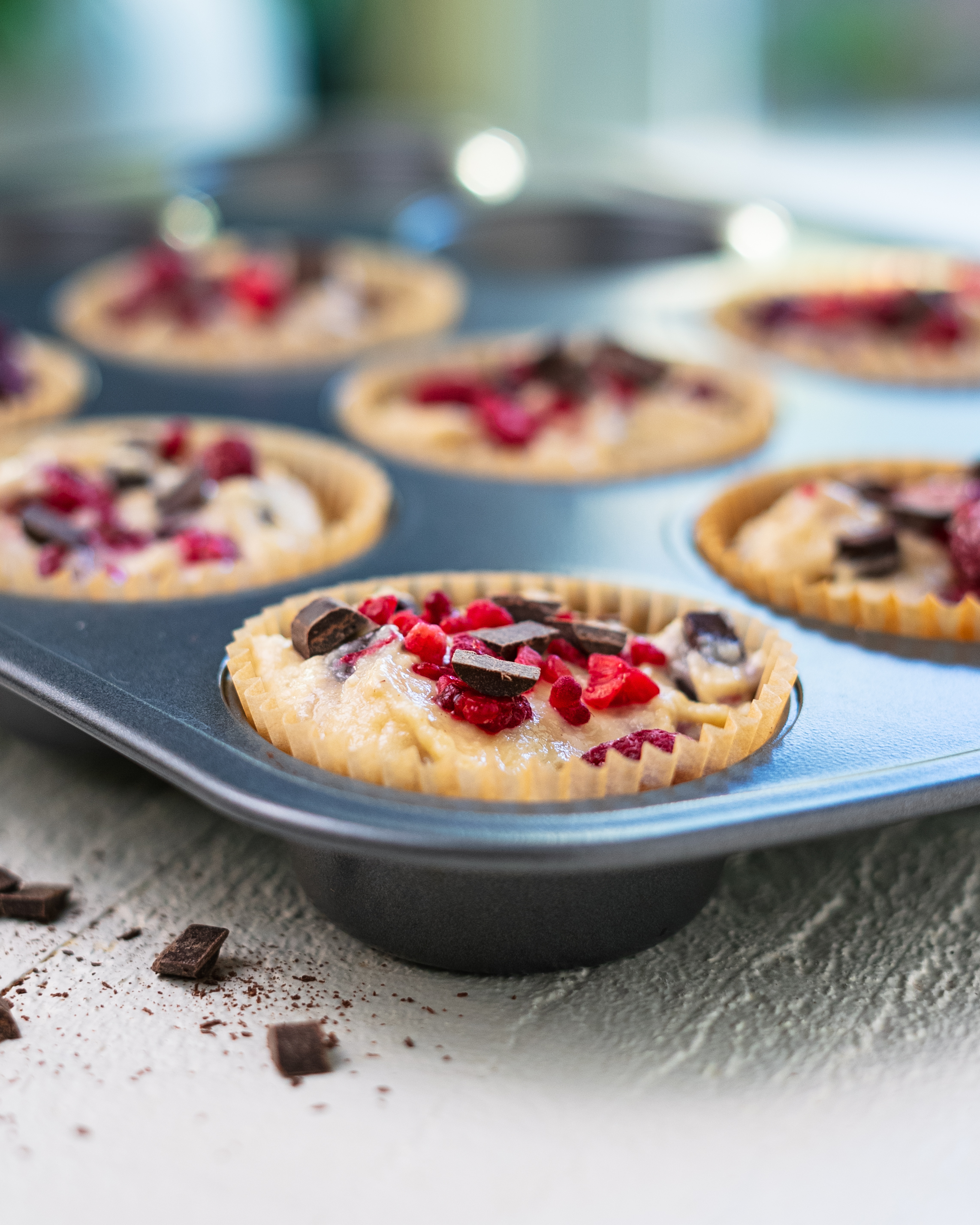 Vegan raspberry chocolate chip muffins in a muffin tin fresh from the oven