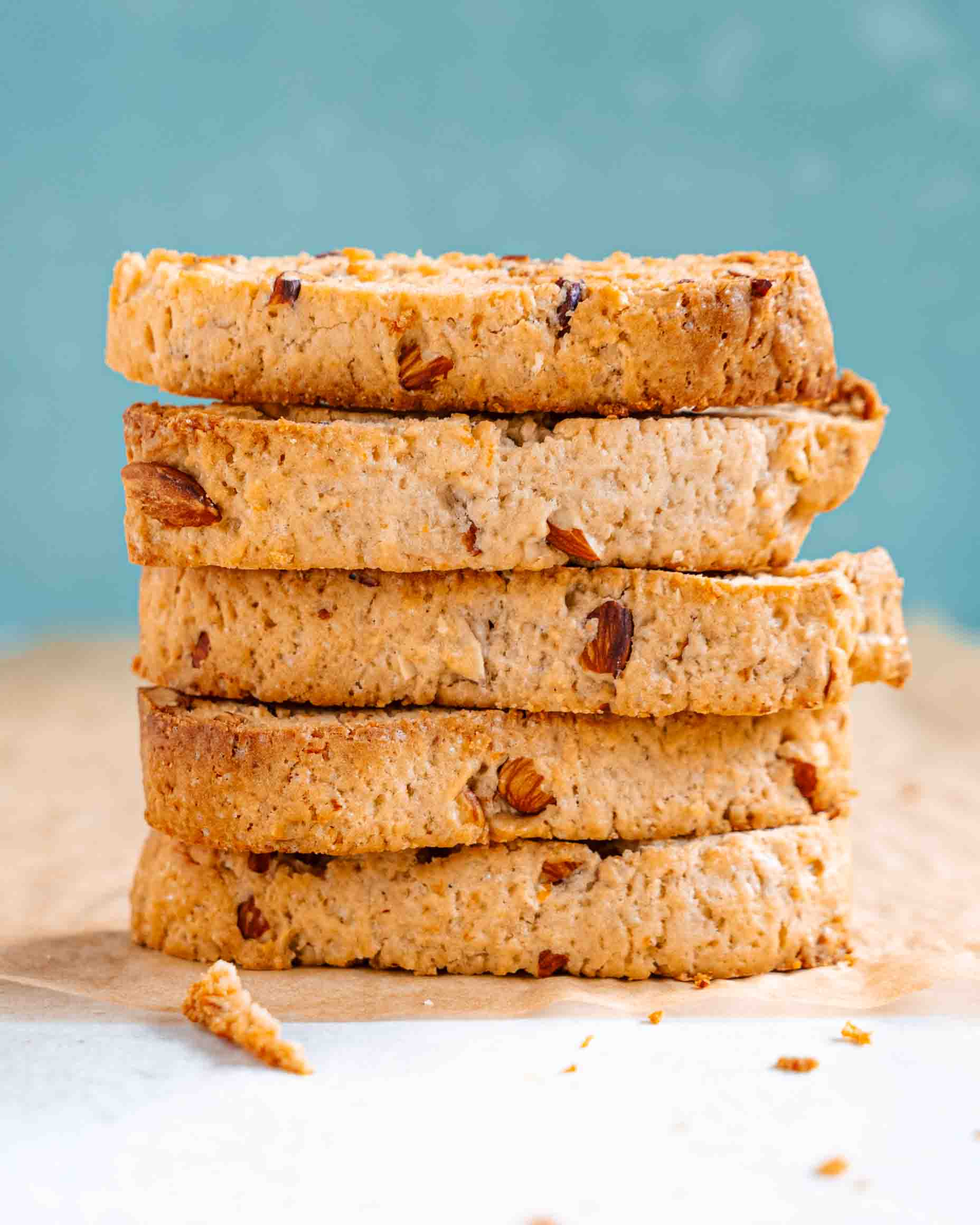 Vegan almond biscotti stacked on a white plate next to a cup of coffee