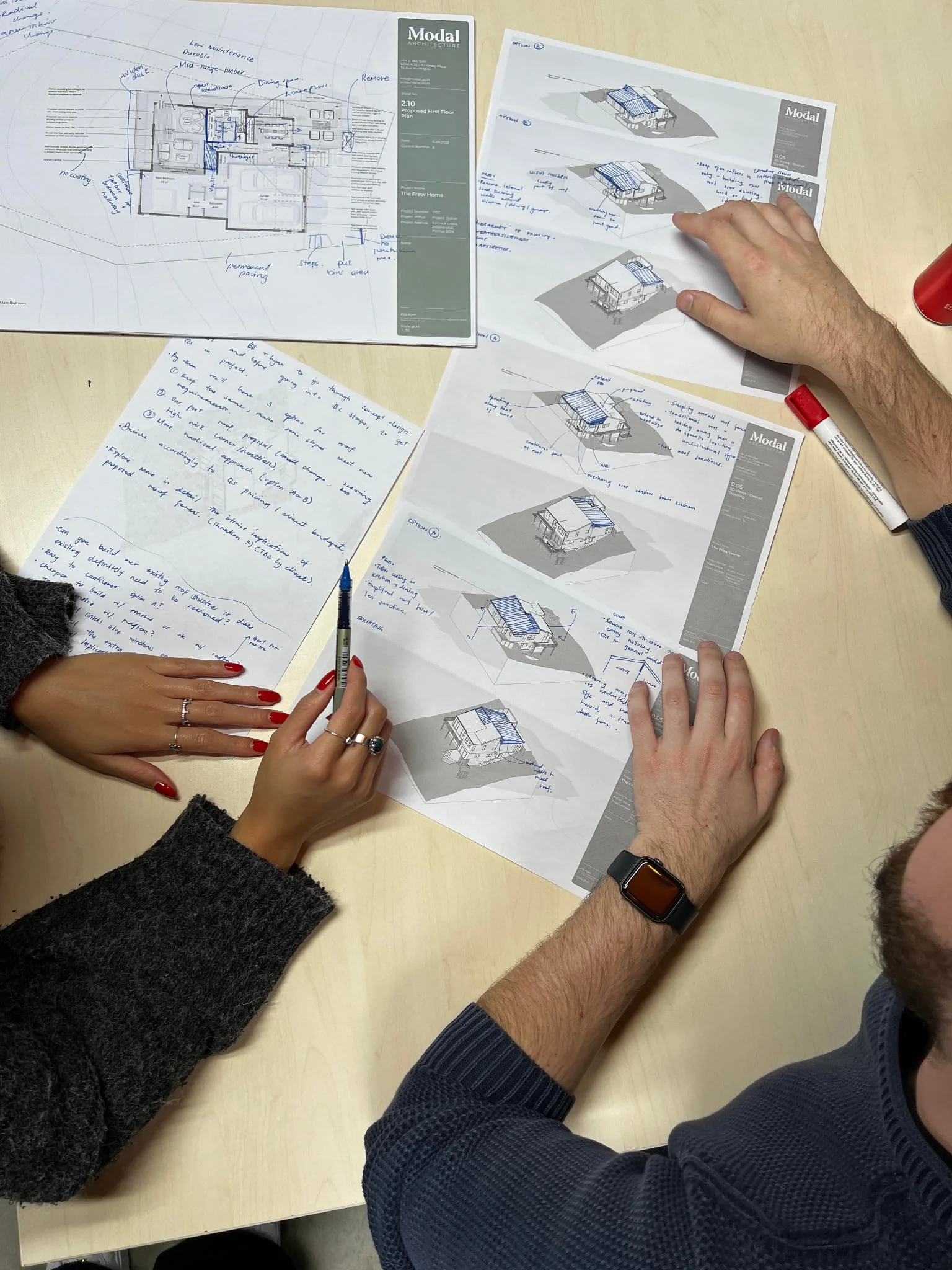 People reviewing architectural plans and drawings on a worktable.