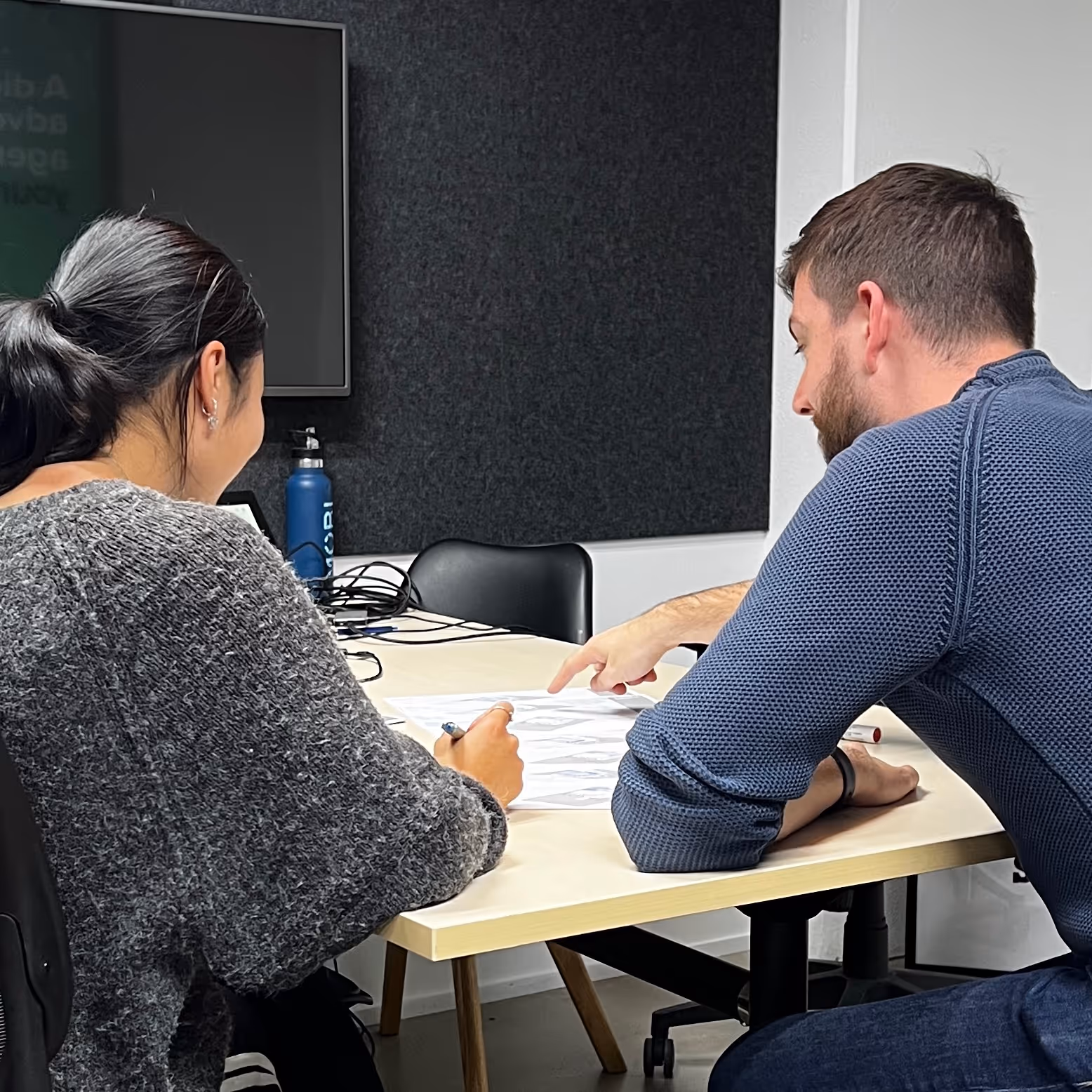 Two people sitting at a table reviewing and discussing papers with sketches or diagrams.  Modal Architecture. New Zealand.