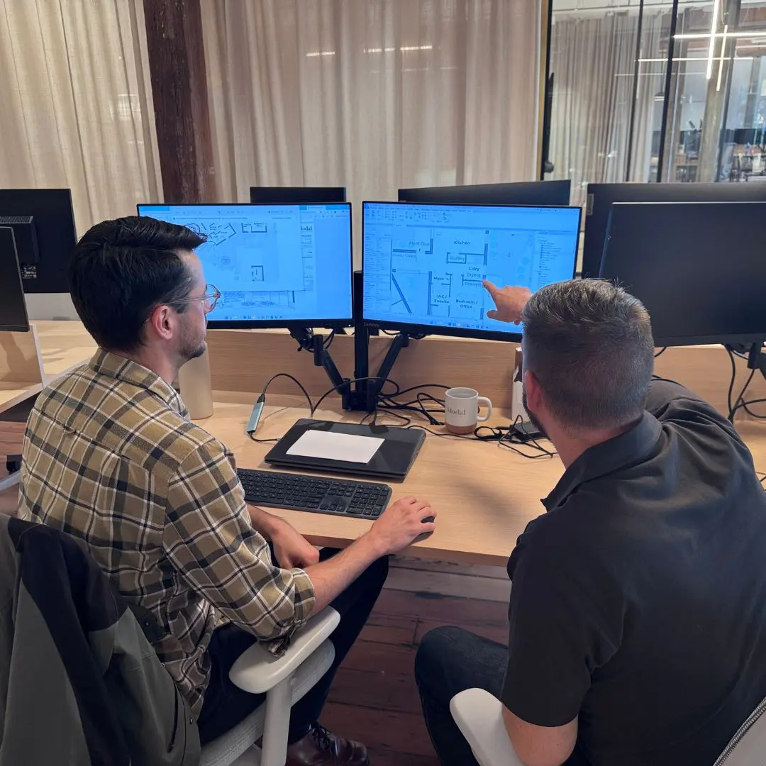 Modal Architecture team members collaboratively reviewing residential architectural drawings and design documentation in the studio.