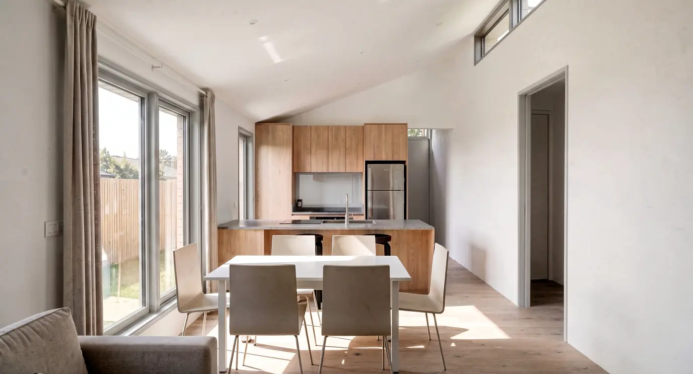 Open plan kitchen and dining area in Modal Architecture's Tui Two home, with timber cabinetry, kitchen island and generous natural light.