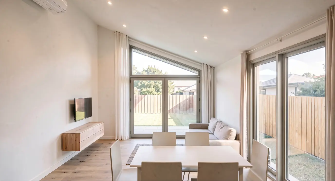 Light filled living room in the Nest Series Takahē Three home by Modal Architecture, featuring expansive garden facing glazing, timber flooring and contemporary interiors.