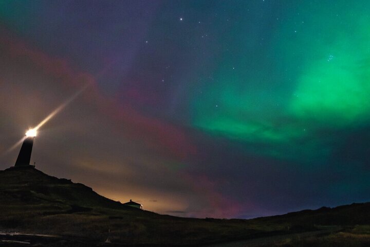 Northern Lights tour participants enjoying hot chocolate under aurora