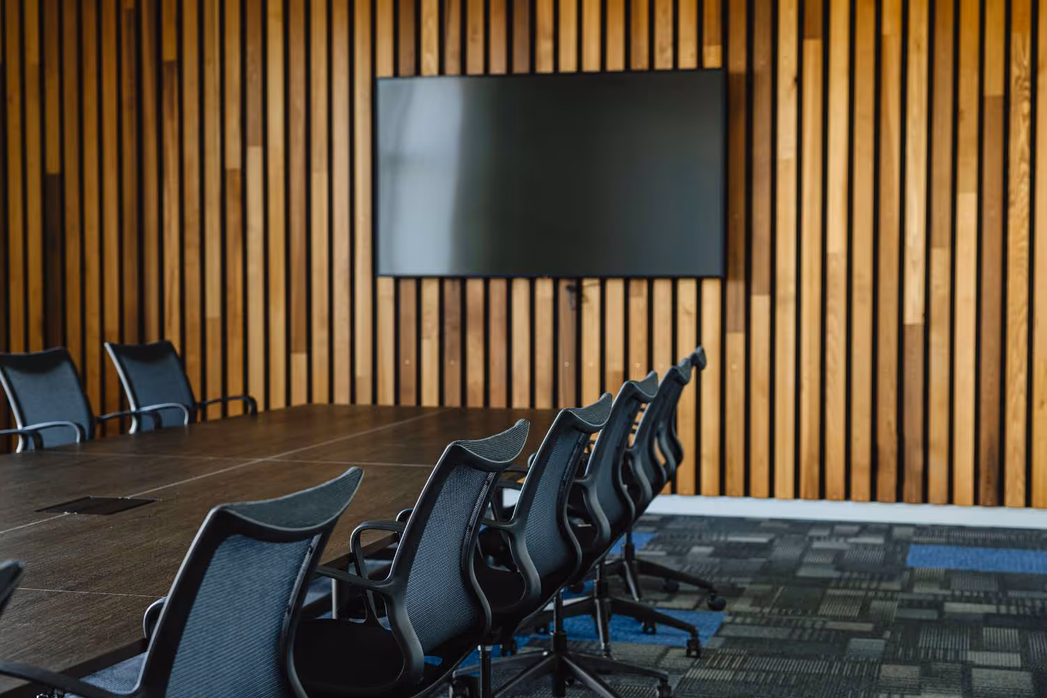 boardroom table and chairs with tv on wooden wall