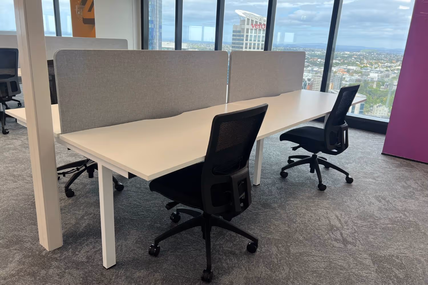 back to back office desk with grey partition screens and chairs