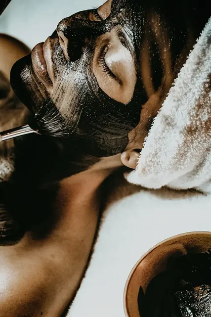 Woman receiving a charcoal facial mask treatment 
