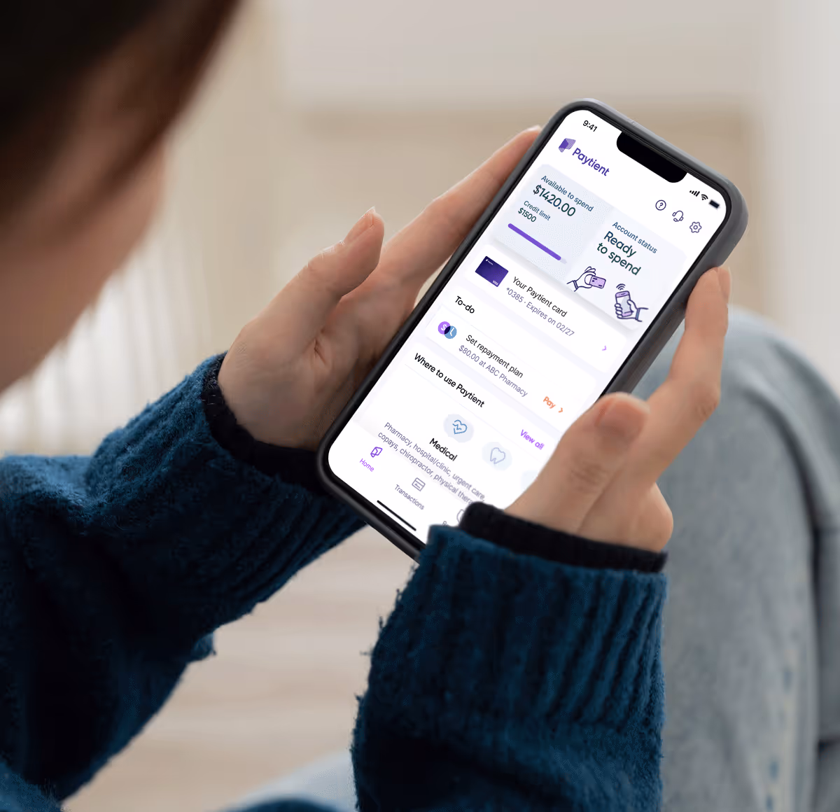 The Paytient App home screen on a mobile device is shown from an over-the-shoulder perspective of a woman.