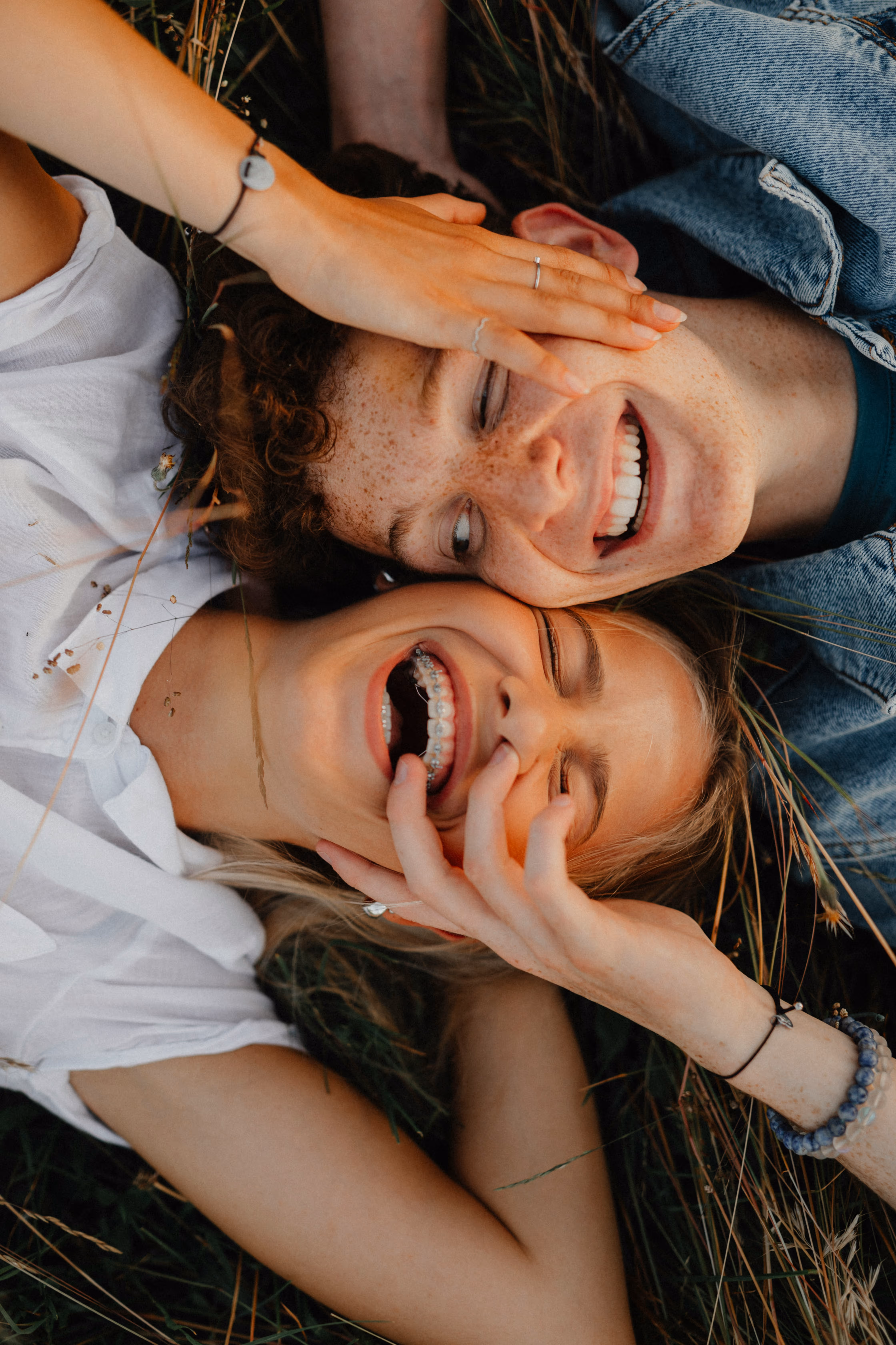 Two people smiling while laying in the grass.
