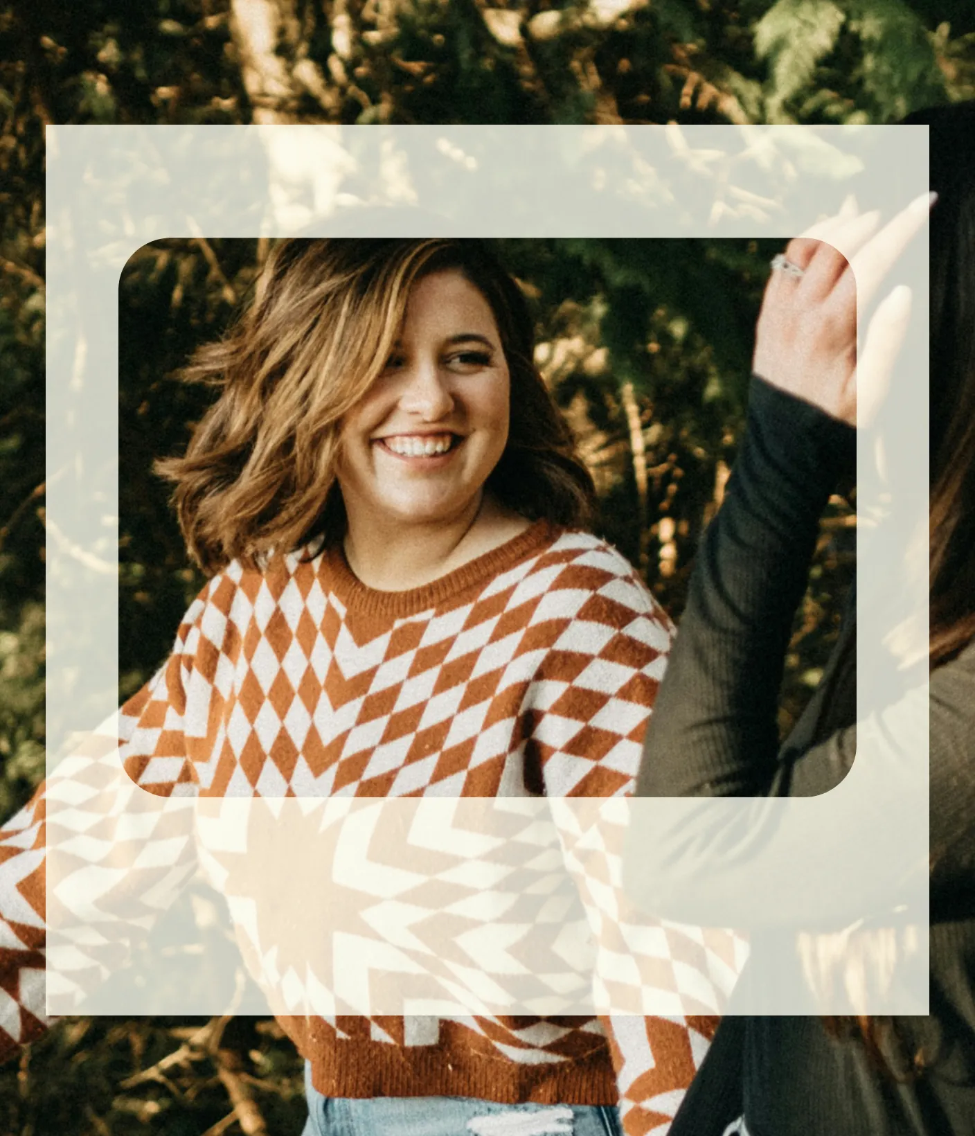 Mujer sonriente con cabello hasta los hombros, vistiendo un suéter con estampado marrón y blanco al aire libre.