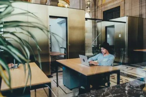 A developer working on a laptop in a modern coworking space, illustrating cloud-based Kubernetes development.