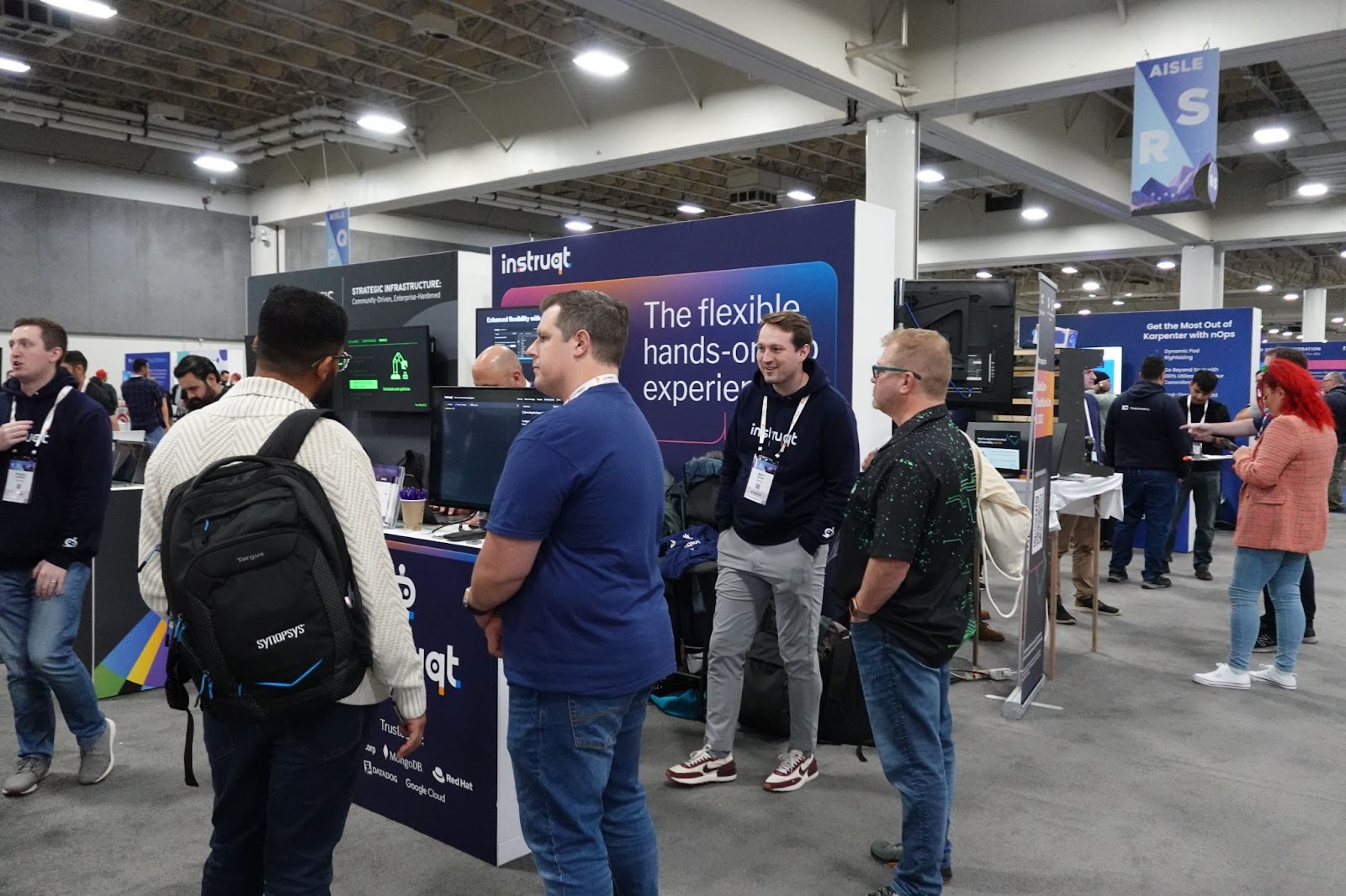 Attendees gather at the Instruqt booth promoting 'the flexible hands-on experience' at a tech conference expo hall.