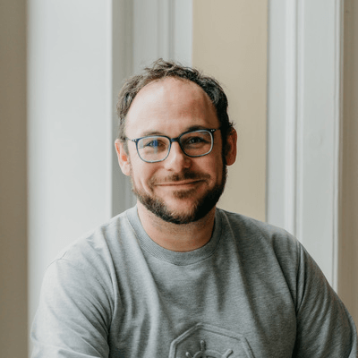 Raphaël Pinson, smiling headshot in a navy t-shirt and blue rectangular glasses against a neutral background.