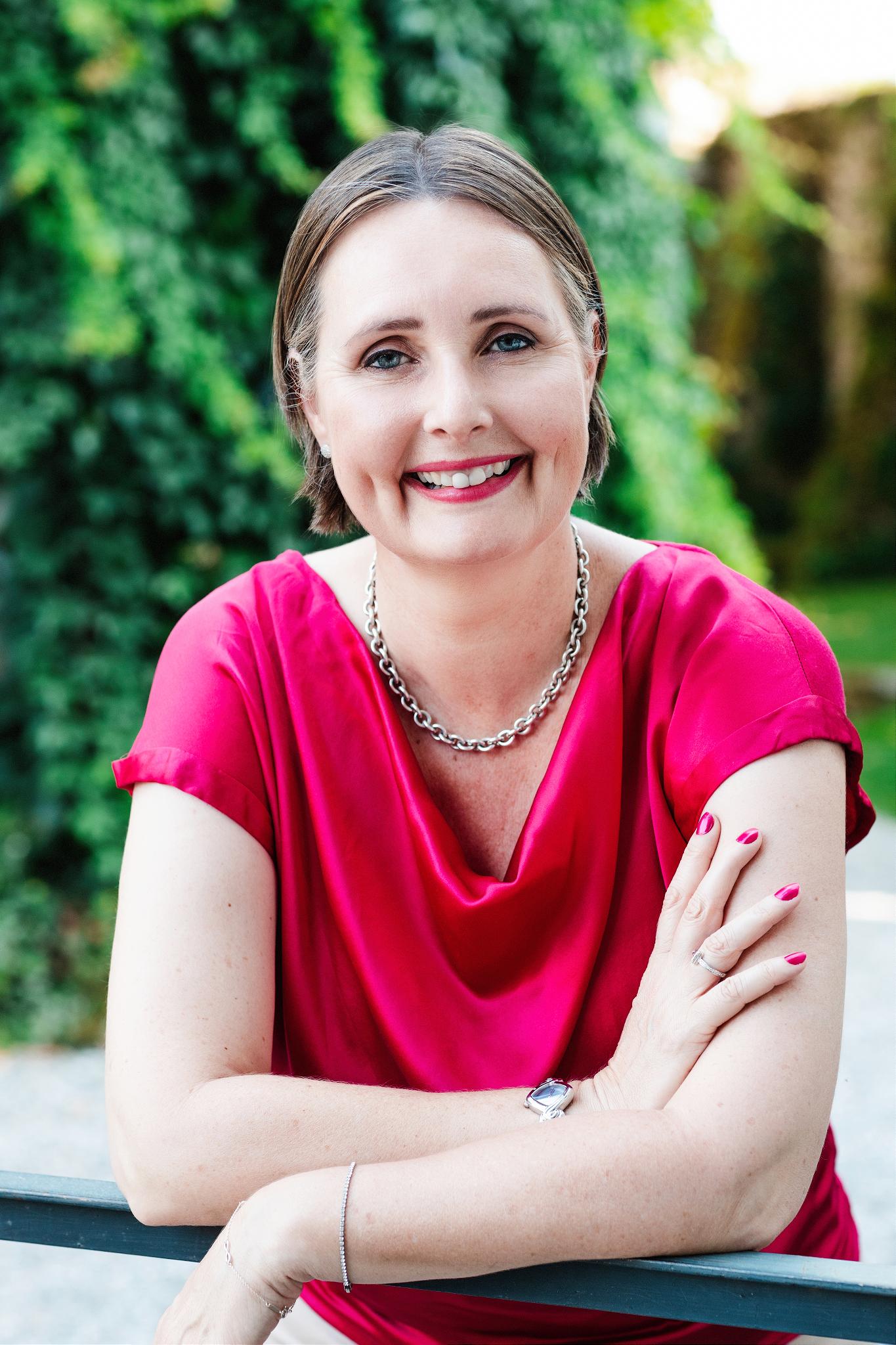 Woman in red dress smiling into the camera.