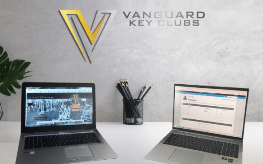 Vanguard Key Clubs workspace with two laptops and brand logo